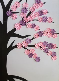 paper flowers are arranged on the side of a tree