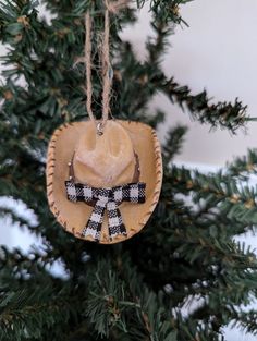 a cowboy hat ornament hanging from a christmas tree with black and white checkered ribbon