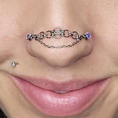 a woman's nose has a chain around it and is wearing a nose ring