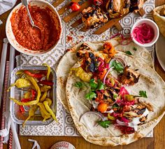 an assortment of tacos and sauces on a table