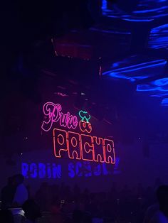 the neon sign is lit up in front of an audience at a concert or club