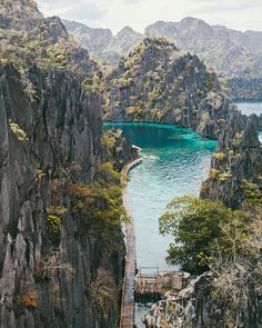 an aerial view of a mountain lake surrounded by trees and rocks, with a wooden walkway leading to the water