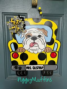 a door hanger that has a dog in the back of a yellow bus on it