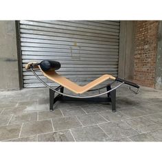 a wooden and metal chaise lounger sitting in front of a garage door