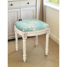 a white vanity stool with a blue flowered seat cover on it in front of a dresser