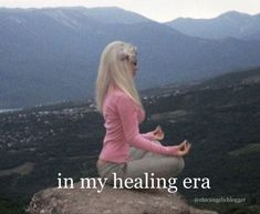 a woman sitting on top of a rock with her hands in the air while meditating