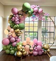 the balloon arch is decorated with pink, green and gold balloons