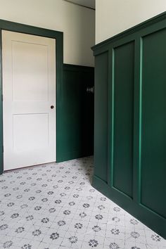 an empty room with green doors and tile flooring on the ground next to a white door