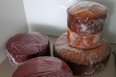 three round pastries wrapped in plastic sitting next to each other on top of a counter