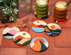 four coasters sitting on top of a red tile floor next to a potted plant