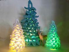 three crocheted christmas trees are lit up with green and white lights on them