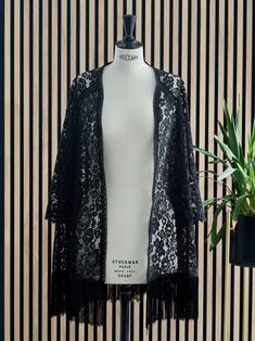 Three-quarter length black lace kimono with long, wide sleeves that ends in beautiful lace details. The length of the sleeve is also three quarters, it has crochet straps on the front and back and borders the entire neckline. On the bottom it has black fringes that make a nice movement when walking. Ideal for any type of look, it is a very versatile garment that can be combined with jeans or a dress for a more formal event. Long Sleeve Fringe Kimono For Festivals, Bohemian Lace Kimono, Festival Long Sleeve Kimono With Fringe, Long Sleeve Festival Kimono With Fringe, Festival Lace Kimono With Lace Trim, Bohemian Long Sleeve Kimono With Fringe, Long Lace Kimono With Lace Trim, Spring Long Sleeve Fringed Kimono, Spring Fringe Long Sleeve Kimono