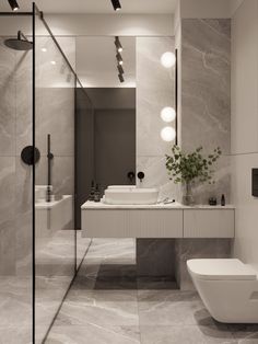 a bathroom with a toilet, sink and large mirror in the wall next to it