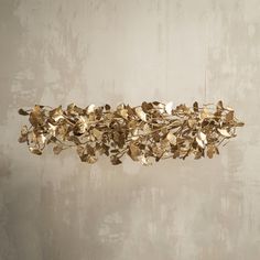 a gold leaf chandelier hanging from the ceiling in front of a white wall