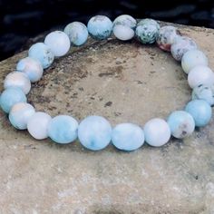 Dominican Larimar Gemstone Beaded Bracelet, Atlantis Dolphin Stone, Calm Luck and Enlightenment, Leo Birthstone, Beach Vibe, Stackable One round Larimar bead to symbolizes one world.  Two oval Larimar beads represent the Sky that stretches endlessly in each direction.  Completing the circle are a carefully selected synergy of natural blue green white and red Larimar gemstone beads laced with copper matrix.  They symbolize the Sea, its' coral, its' depths, and its' mysteries.   ✨The Pfeffars Difference ✨ ☺ Happiness Guaranteed. Our top priority is your complete happiness. Which means we stand by our crystal bracelets 100% no matter what. If you have a problem, we will solve it. Remake it. Whatever it takes. Just reach out to us within 14 days of receiving your bracelet. We're here for you. Adjustable Aquamarine Bracelets With Natural Stones, Adjustable Aquamarine Beaded Bracelet With Natural Stones, Adjustable Aquamarine Beaded Bracelets With Natural Stones, Turquoise Aquamarine Beaded Bracelets With Natural Stones, Spiritual Gemstone Beaded Bracelets For The Beach, Aquamarine Turquoise Bracelet For Healing, Turquoise Aquamarine Healing Bracelet, Spiritual Aquamarine Round Beads Jewelry, Spiritual Aquamarine Turquoise Bracelets