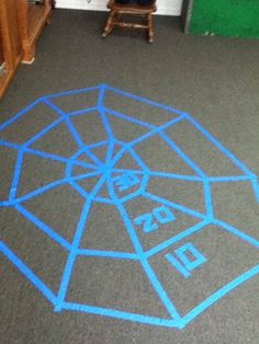 a child's drawing on the floor with blue chalk in front of them and a chair behind it