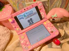 a pink toy laptop sitting on top of a bed next to toys and other items