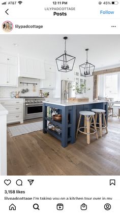 an instagramted photo of a kitchen with white cabinets and blue island