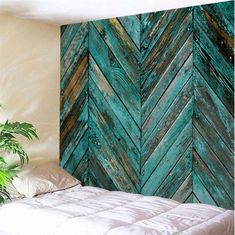 a bed sitting under a wooden wall next to a plant