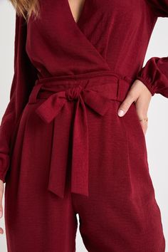 The Lulus In the City Burgundy Surplice Long Sleeve Jumpsuit is a look that can take you where you wanna go! Lightweight flat woven fabric sweeps chicly across long sleeves and a flirty surplice bodice with pleated detail and a back keyhole (secured by two round covered buttons). Paper bag waist (with belt loops and a tying sash belt) adds unique flair atop slim cropped pant legs, making this jumpsuit a stylish choice for day or night! Hidden side seam pockets. Hidden back zipper/clasp. Fit: Thi Long Sleeve Tie Waist Jumpsuits For Loungewear, Long Sleeve Jumpsuit With Tie Waist For Loungewear, Long Sleeve Tie Waist Jumpsuits And Rompers For Loungewear, Long Sleeve Jumpsuits And Rompers For Brunch, Chic Long Sleeve Jumpsuits For Brunch, Chic Long Sleeve Jumpsuits And Rompers For Brunch, Long Sleeve Jumpsuits And Rompers For Workwear, Tie Waist Long Sleeve Jumpsuits And Rompers, Long Sleeve Solid Jumpsuit With Tie Waist