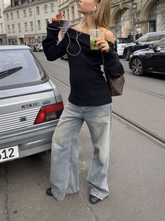 a woman standing next to a parked car and listening to music on her headphones