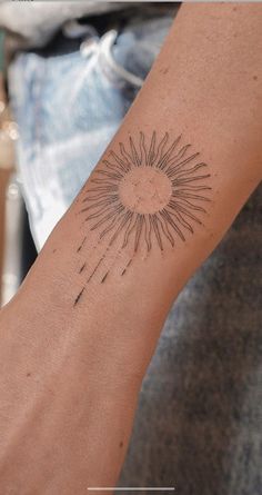 a person's arm with a tattoo on it that has a sun in the middle