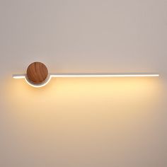 a white wall with a wooden object on it's side and light coming from the top