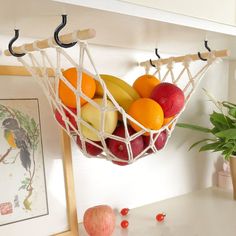 a fruit basket hanging on a wall next to a potted plant and an apple