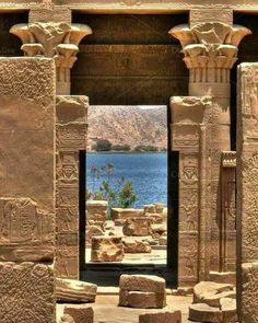 an ancient building with columns and water in the background