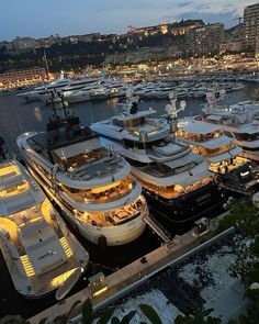 many boats are docked in the harbor at night, with lights shining on them and buildings in the background