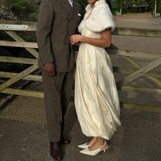 a man and woman standing next to each other in front of a wooden fence with trees