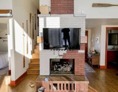 a living room with a fire place in the middle of it and a tv on top of a brick fireplace