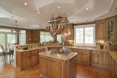 a large kitchen with wooden cabinets and marble counter tops, an island in the middle