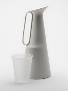 a white pitcher and a glass on a white background with one cup in the foreground