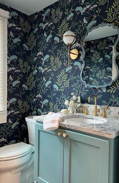 a bathroom with blue wallpaper and gold fixtures