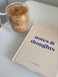 a book sitting on top of a white table next to a cup of coffee and a mug