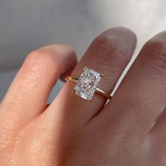 a woman's hand with a diamond ring on top of her finger and the other hand holding an engagement ring