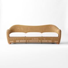 a wicker couch with white cushions on it's back and arms, in front of a white background