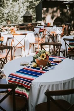 tables and chairs are set up outside for an outdoor event with sunflowers on the table