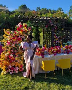 a woman standing next to a table covered in flowers