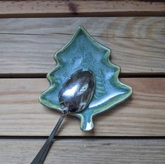 a spoon sitting on top of a green leaf shaped dish with a tree design in the center