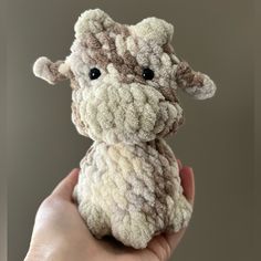 a hand holding a small stuffed animal in it's left hand