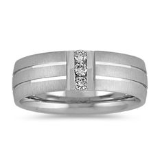 This dynamic 7mm men's wedding ring features three round diamonds  at approximately .15 carat total weight  that were hand-matched for consistent fire and sparkle. The diamonds are channel-set in quality 14 karat white gold with both brushed and polished finishes. Round Diamond Wedding Band, White Gold Diamond Band, Round Diamonds Wedding Band, Wedding Organizer Planner, Gold Diamond Band, 22 Carat Gold, Men's Wedding Ring, Platinum Jewelry, Diamond Wedding Band