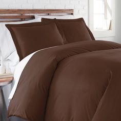 a bed with brown and white comforters in a room next to a brick wall