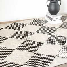 a black vase sitting on top of a rug next to a white and black floor