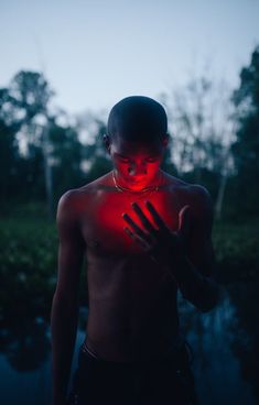 a shirtless man with his hands on his chest and glowing red light around him