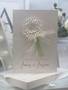 a wedding card with a white flower on it and congratulations written in the middle, sitting on a table