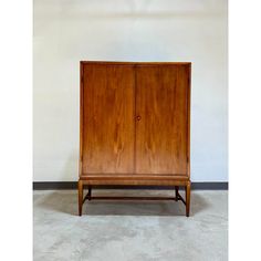 a wooden cabinet sitting on top of a cement floor next to a wall with a door