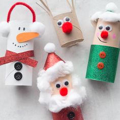 three paper tubes decorated like santa claus and snowmen with red noses, nose rings and green hair