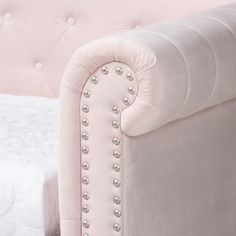 the back of a pink couch with pearls on it's arm and foot rest